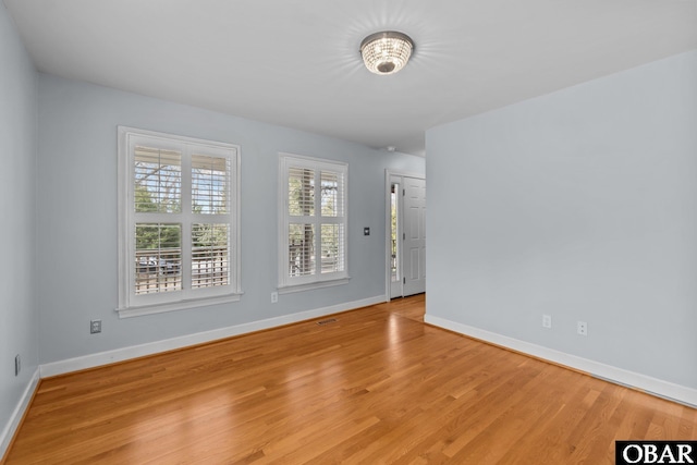 empty room with baseboards, visible vents, and light wood-style floors