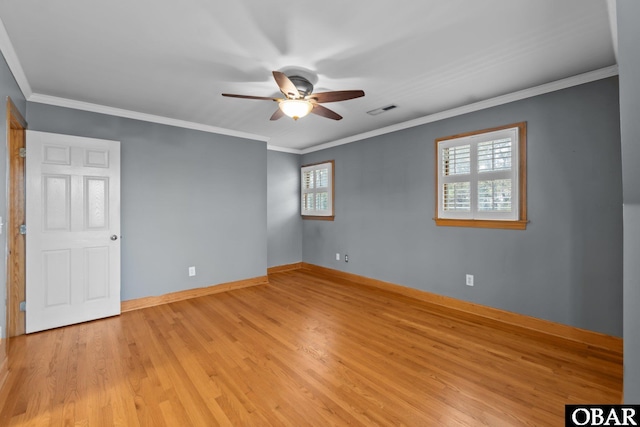 empty room featuring baseboards, ornamental molding, visible vents, and light wood-style floors