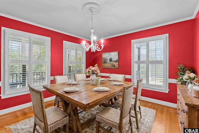 dining area with baseboards, light wood-style floors, an inviting chandelier, and crown molding