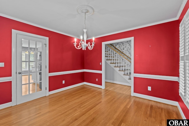 unfurnished dining area featuring a chandelier, ornamental molding, wood finished floors, and baseboards