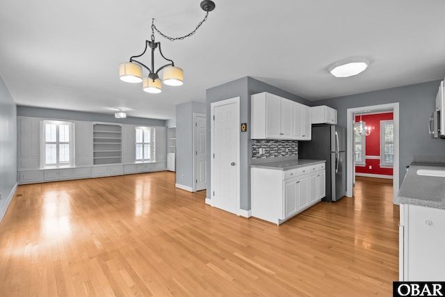 kitchen featuring a notable chandelier, light wood-style flooring, appliances with stainless steel finishes, open floor plan, and white cabinetry