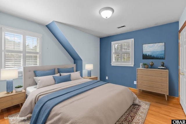 bedroom featuring visible vents, multiple windows, and wood finished floors