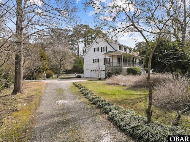 view of side of property featuring a porch, driveway, and an attached garage