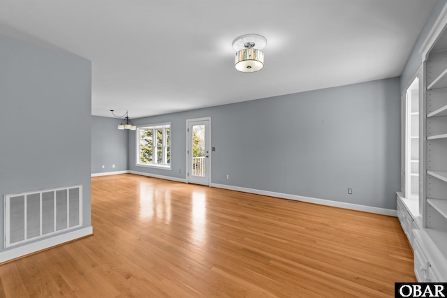 unfurnished living room with light wood-style flooring, visible vents, and baseboards