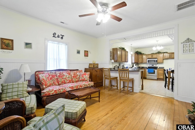 401 E Queen St, Edenton, NC 27932 - living area with light wood-type flooring, a wainscoted wall, ceiling fan, a chandelier, and ornamental molding