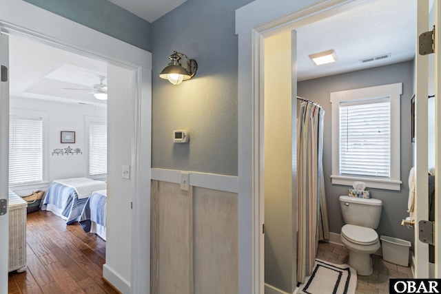 bathroom featuring toilet, a ceiling fan, curtained shower, visible vents, and baseboards