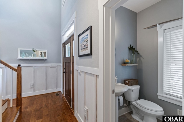 bathroom with toilet, visible vents, a wainscoted wall, and wood finished floors