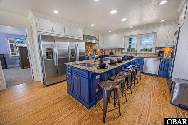 1459 Ocean Pearl Rd Lot 2, 3A, 3B, Corolla, NC 27927 - kitchen featuring stainless steel appliances, blue cabinets, wall chimney range hood, white cabinets, and a kitchen bar