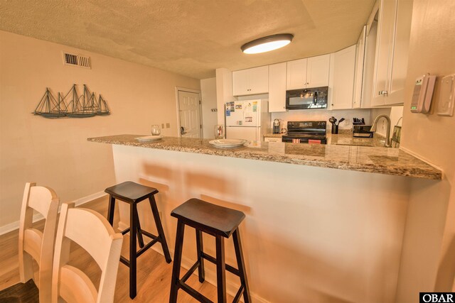 24256 Resort Rodanthe Dr Unit 6B, Rodanthe, NC 27968 - kitchen with a peninsula, black appliances, visible vents, and white cabinets