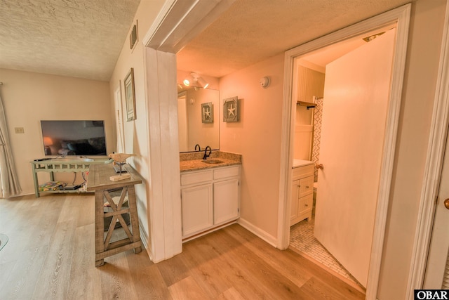 24256 Resort Rodanthe Dr Unit 6B, Rodanthe, NC 27968 - hallway featuring baseboards, visible vents, a textured ceiling, light wood-type flooring, and a sink