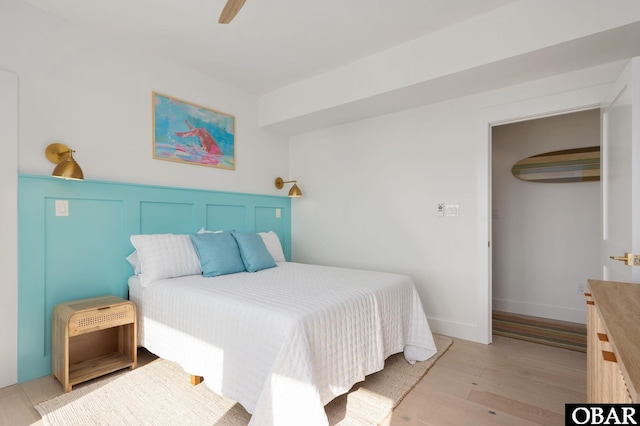 bedroom featuring light wood-type flooring, baseboards, and ceiling fan