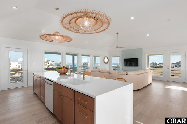 kitchen featuring vaulted ceiling, white dishwasher, light wood finished floors, and a sink