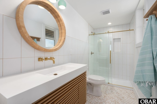 full bathroom featuring visible vents, toilet, a stall shower, tile walls, and vanity