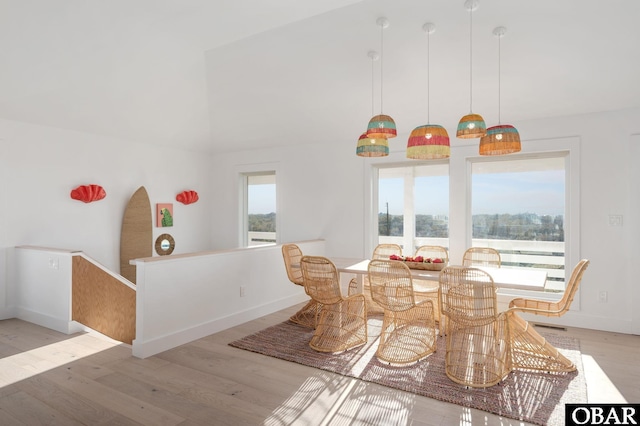 dining area with light wood-style flooring, plenty of natural light, baseboards, and high vaulted ceiling