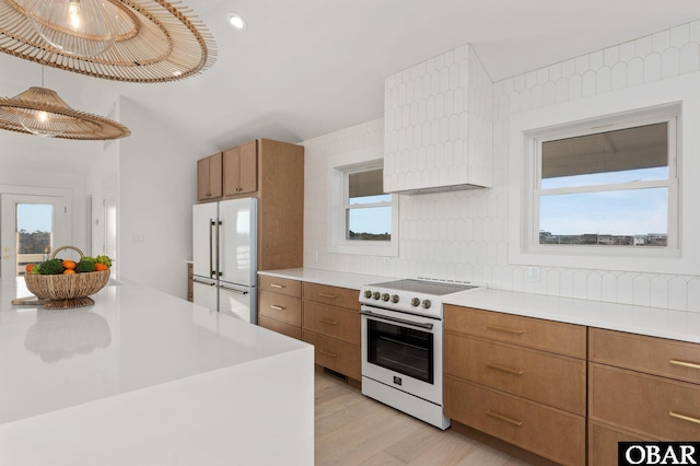 kitchen with white appliances, brown cabinetry, light countertops, light wood-style floors, and tasteful backsplash