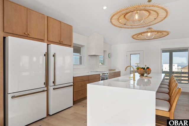 kitchen featuring white appliances, light countertops, light wood-type flooring, and a sink