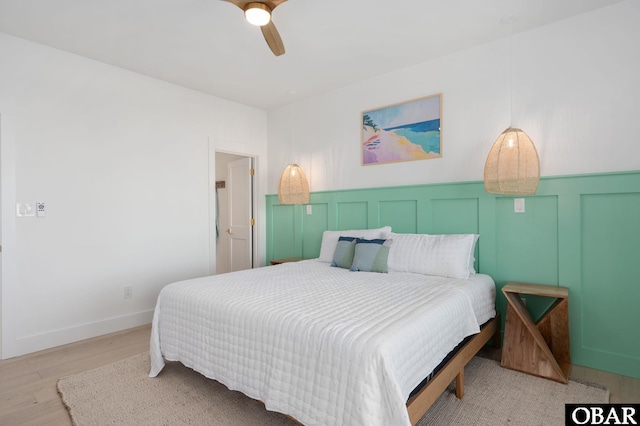 bedroom featuring ceiling fan, wood finished floors, and a decorative wall