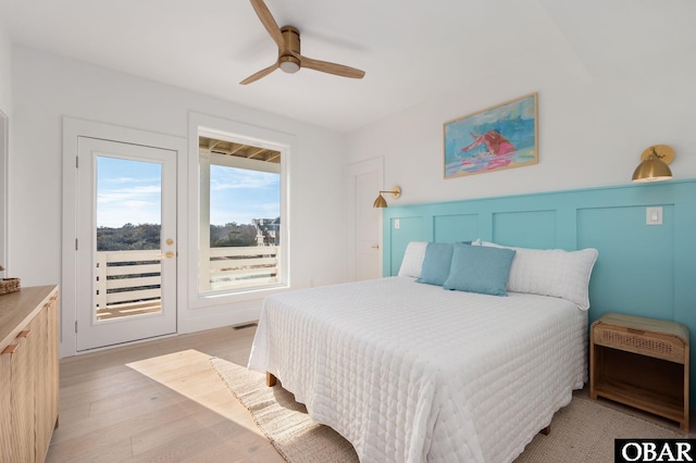 bedroom featuring access to exterior, visible vents, ceiling fan, light wood-type flooring, and wainscoting