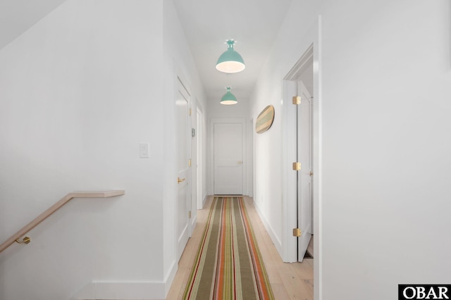 hallway featuring an upstairs landing, light wood-style floors, and baseboards