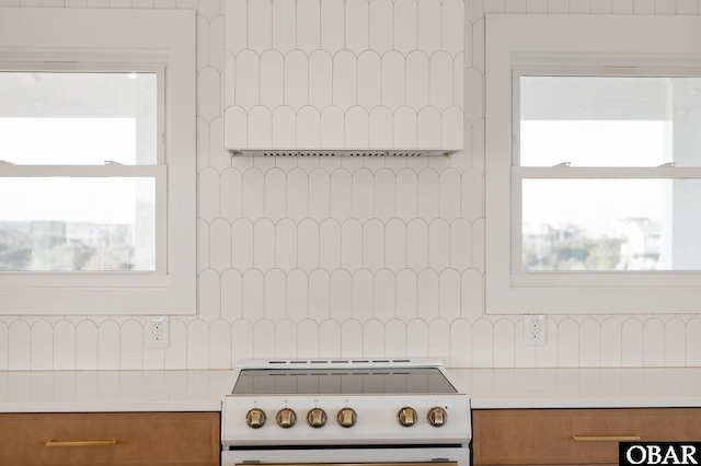 kitchen featuring brown cabinetry, white electric range, backsplash, and light countertops