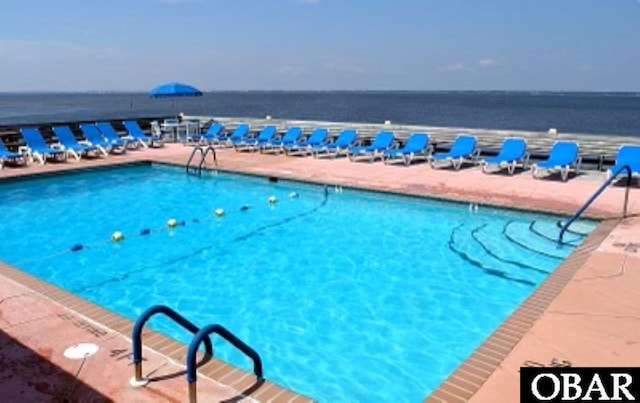 view of swimming pool with a water view and a view of the beach