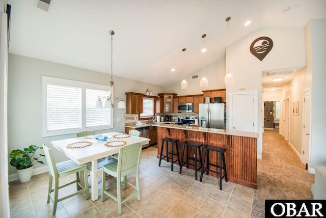 kitchen with stainless steel appliances, light countertops, glass insert cabinets, and decorative light fixtures