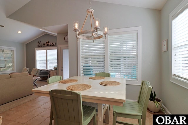 dining room with a chandelier, light tile patterned flooring, lofted ceiling, and a wealth of natural light