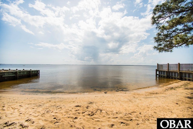 view of dock featuring a water view and a beach view