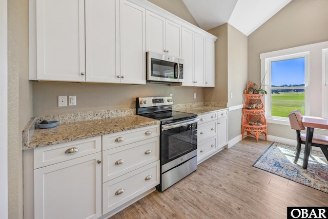 149 Carolina Club Dr Lot 54, Grandy, NC 27939 - kitchen featuring appliances with stainless steel finishes, vaulted ceiling, white cabinetry, light wood-style flooring, and light stone countertops