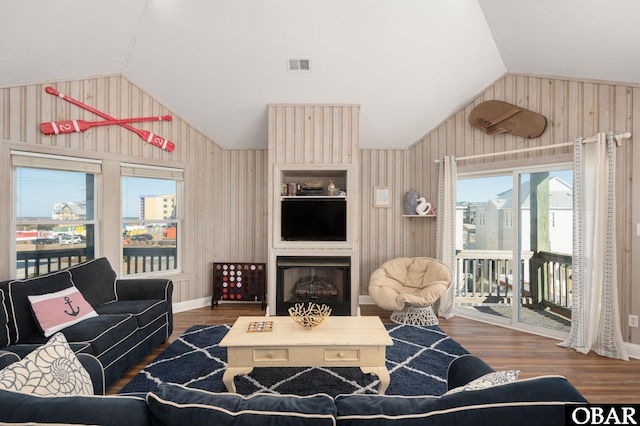 living area featuring a large fireplace, visible vents, vaulted ceiling, and dark wood-style flooring