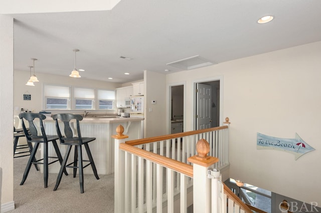 interior space featuring recessed lighting, light carpet, a sink, and an upstairs landing