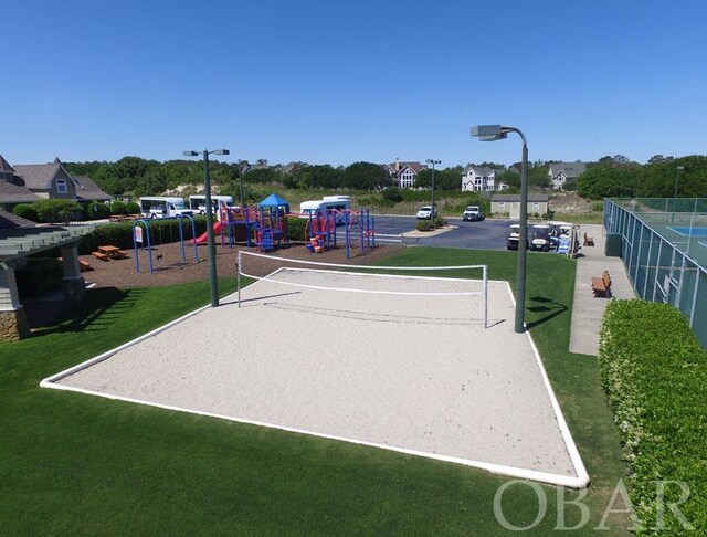 view of property's community with playground community, a yard, and fence