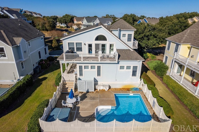 rear view of property with a fenced backyard, a balcony, a shingled roof, a residential view, and a fenced in pool