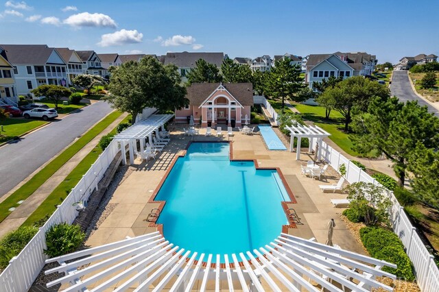 community pool featuring a fenced backyard, a residential view, an outbuilding, a patio area, and a pergola