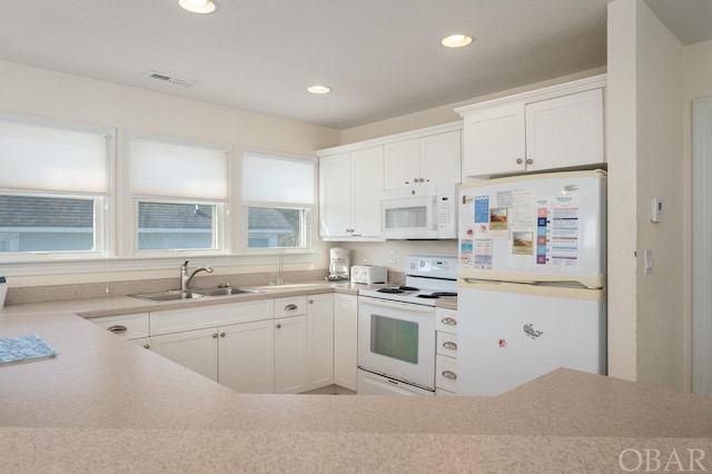 kitchen with white appliances, visible vents, light countertops, white cabinetry, and a sink