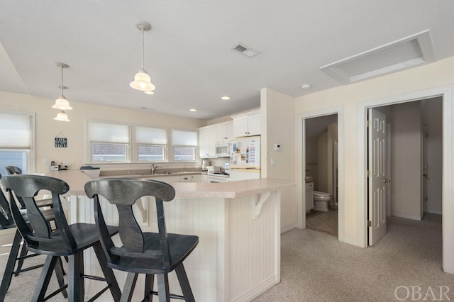 kitchen with decorative light fixtures, light countertops, visible vents, white cabinetry, and white appliances