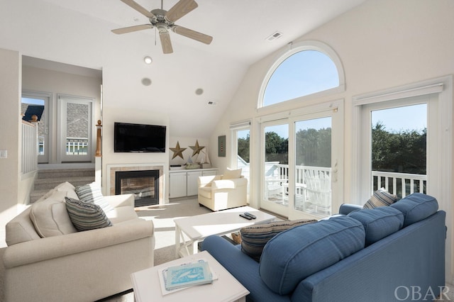 carpeted living room with ceiling fan, high vaulted ceiling, a fireplace with flush hearth, and visible vents