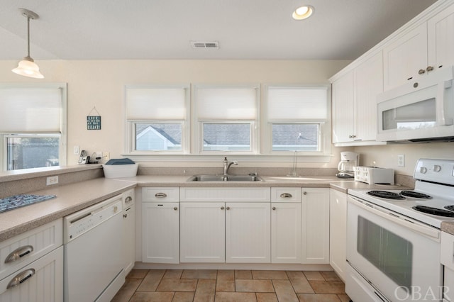 kitchen featuring white appliances, a sink, white cabinetry, light countertops, and decorative light fixtures