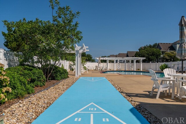 view of property's community featuring a swimming pool, shuffleboard, fence, and a pergola