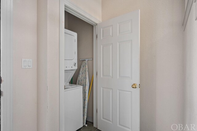 clothes washing area with stacked washer and clothes dryer and laundry area