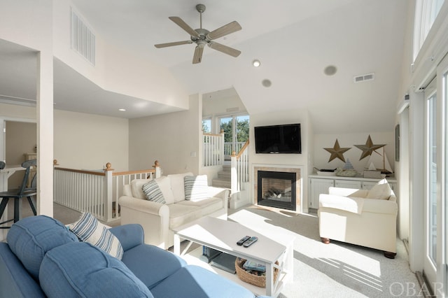 living room featuring high vaulted ceiling, a fireplace, visible vents, and light colored carpet