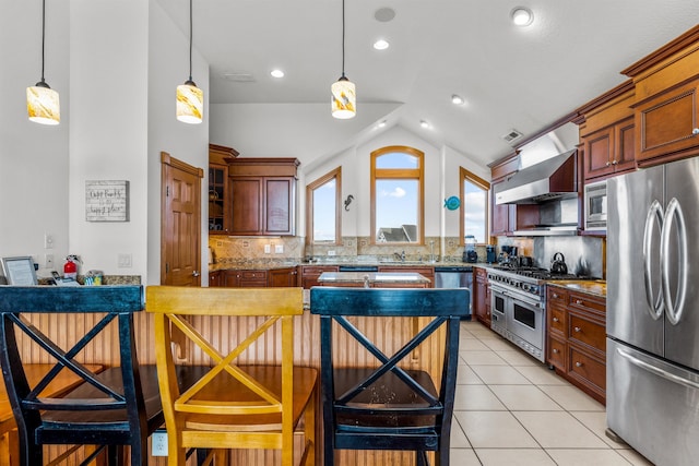 670 Hunt Club Dr Lot 194, Corolla, NC 27927 - kitchen with appliances with stainless steel finishes, wall chimney exhaust hood, decorative backsplash, hanging light fixtures, and vaulted ceiling