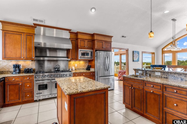 kitchen with wall chimney exhaust hood, a kitchen island, appliances with stainless steel finishes, pendant lighting, and a sink