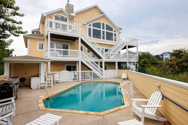 670 Hunt Club Dr Lot 194, Corolla, NC 27927 - back of property with stairs, a patio, an outdoor pool, a chimney, and a balcony