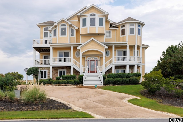 view of front facade with stone siding, stairs, and concrete driveway