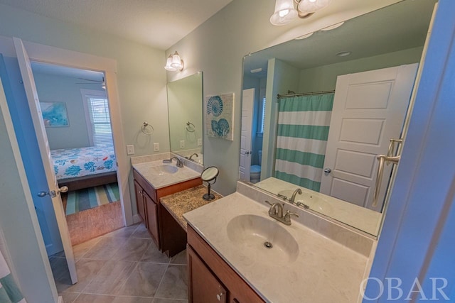 ensuite bathroom with ensuite bathroom, two vanities, tile patterned flooring, and a sink