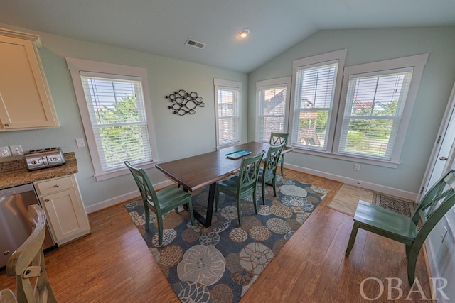 dining space featuring vaulted ceiling, light wood finished floors, visible vents, and baseboards