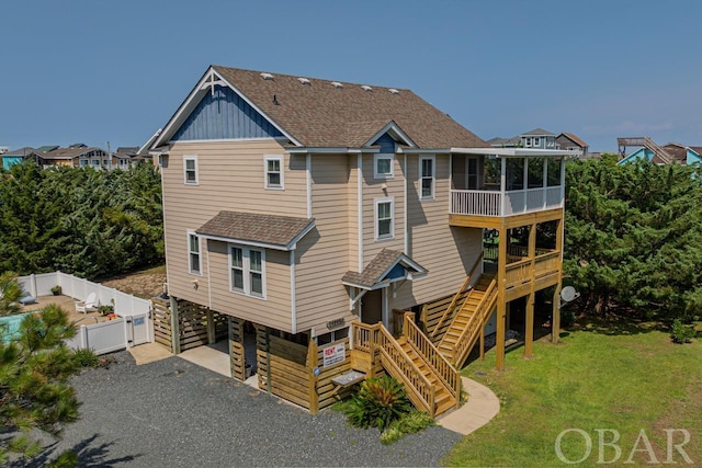 rear view of property with driveway, a shingled roof, a sunroom, a yard, and a carport