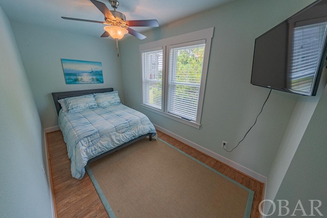 bedroom featuring a ceiling fan, baseboards, and wood finished floors