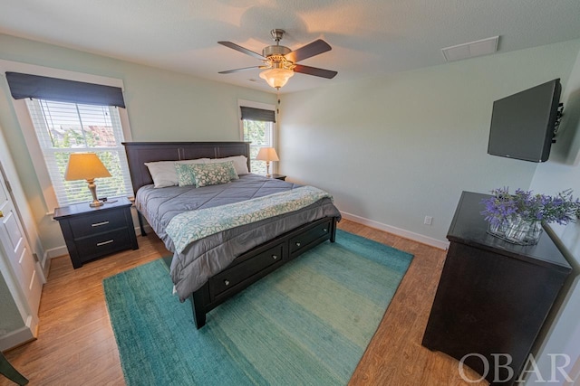 bedroom with a ceiling fan, baseboards, and wood finished floors